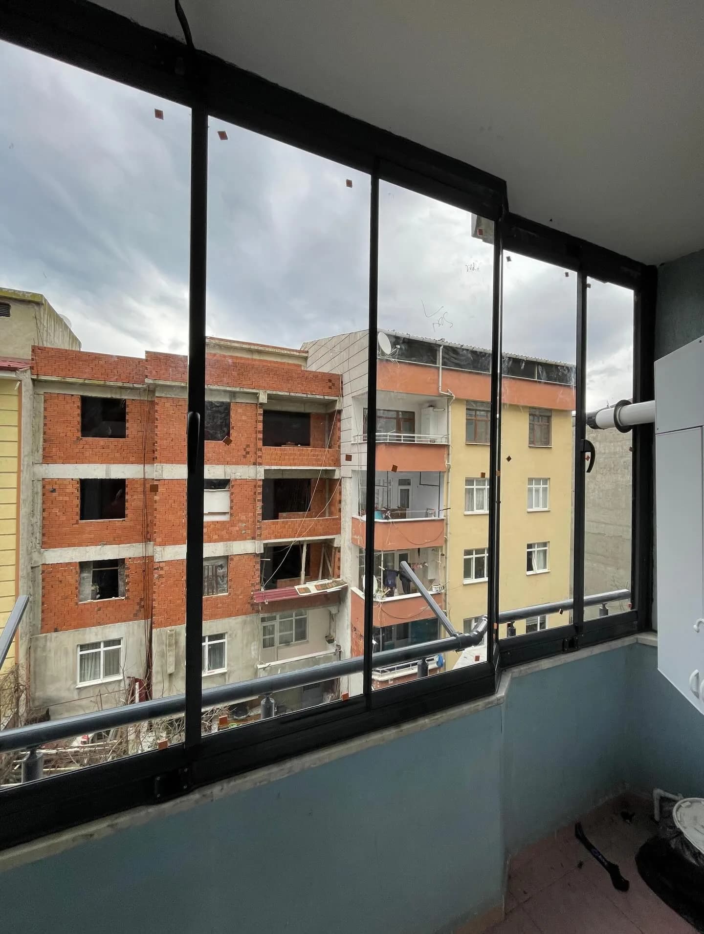 Samsun'da balkona uygulanmış siyah doğramalı sürme cam balkon sistemi, dış cephe manzaralı