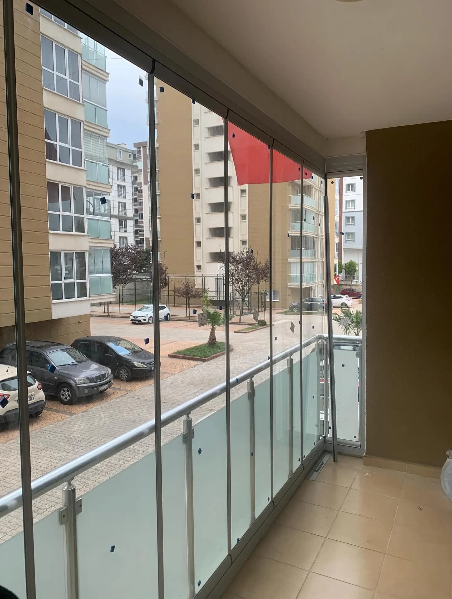 Samsun'da bir balkona uygulanmış çerçevesiz katlanır cam balkon sistemi, buzlu cam korkuluk ve fayans zemin