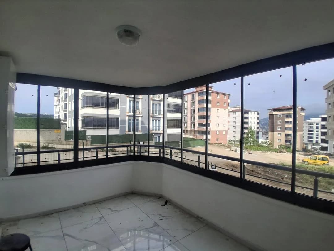 Samsun'da köşe balkona uygulanmış antrasit doğramalı ısıcamlı cam balkon sistemi ve şehir manzarası