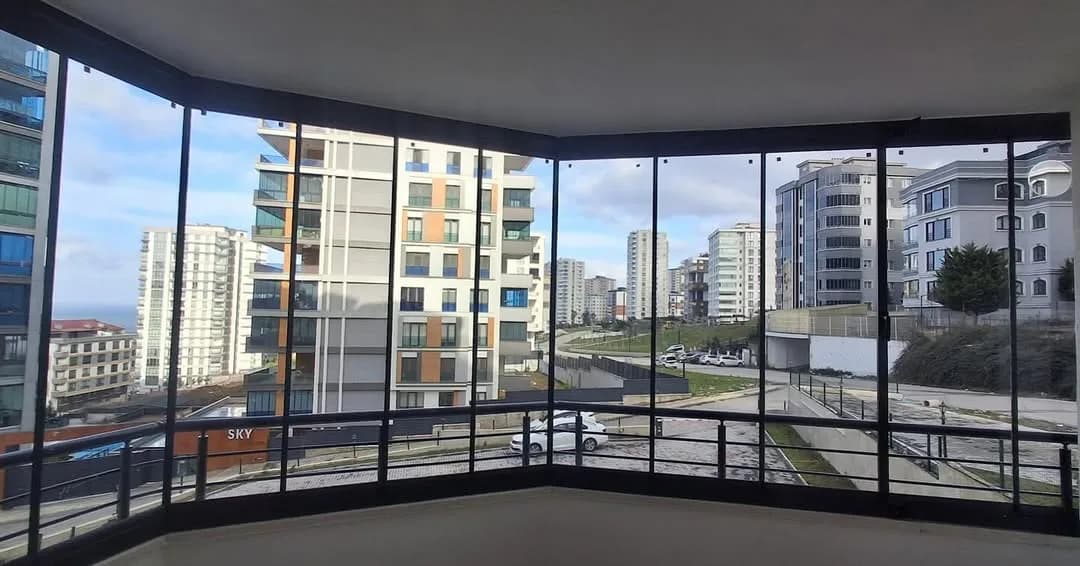 Samsun'da köşe balkona uygulanmış füme çerçeveli katlanır cam balkon ve şehir manzarası