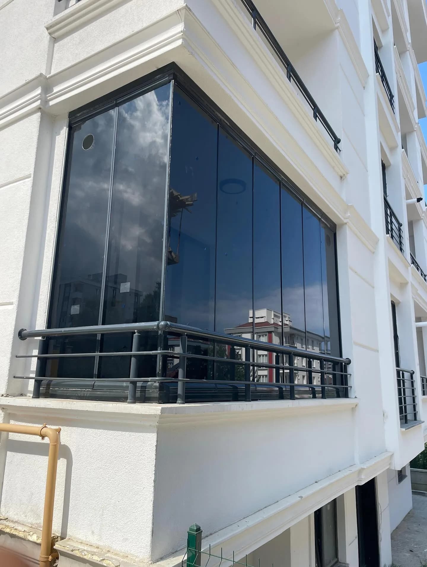 Samsun'da köşe balkona uygulanmış füme renkli çerçevesiz katlanır cam balkon sistemi