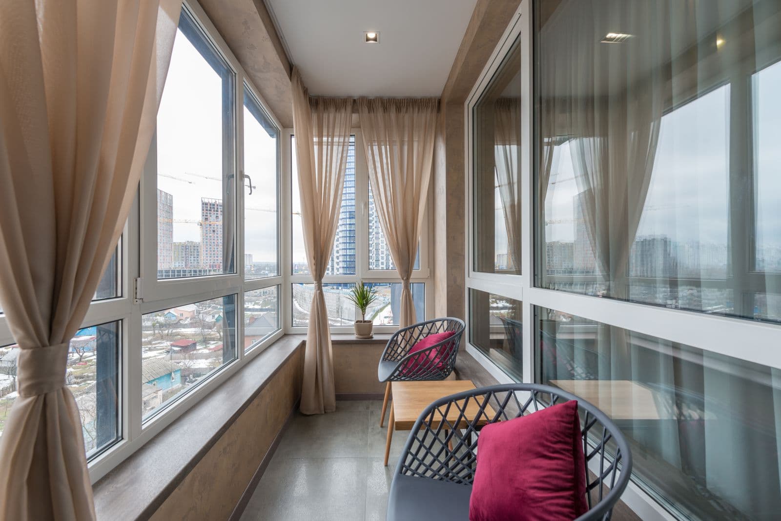 Isıcamlı doğramayla kapatılmış, şehir manzaralı konforlu balkon oturma köşesi