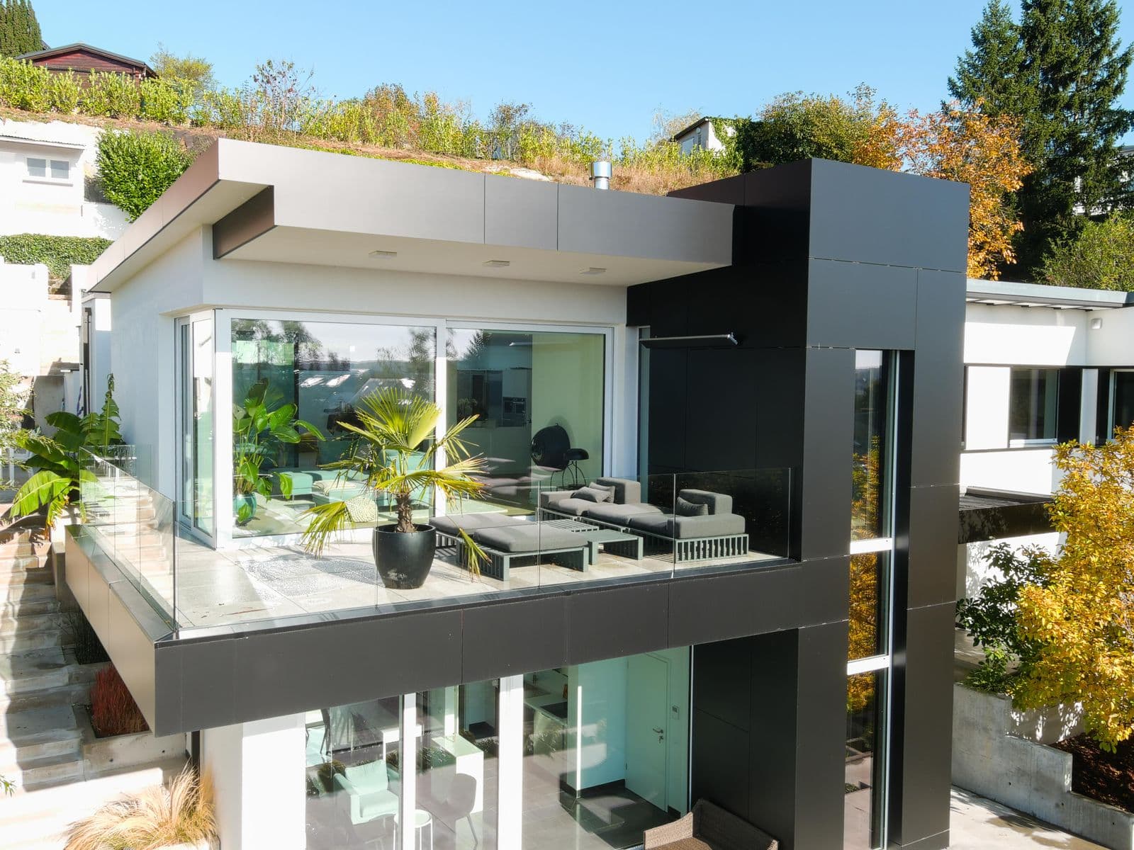 Cam panellerle kapatılmış modern teras balkonda şezlonglu oturma alanı